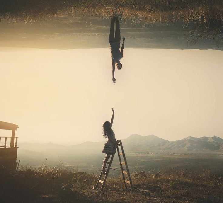 Two people reaching towards one another across an inverted landscape